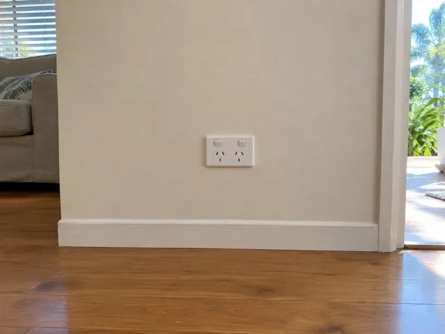 White double power point on a painted wall above skirting in a timber-floored room in Tugun